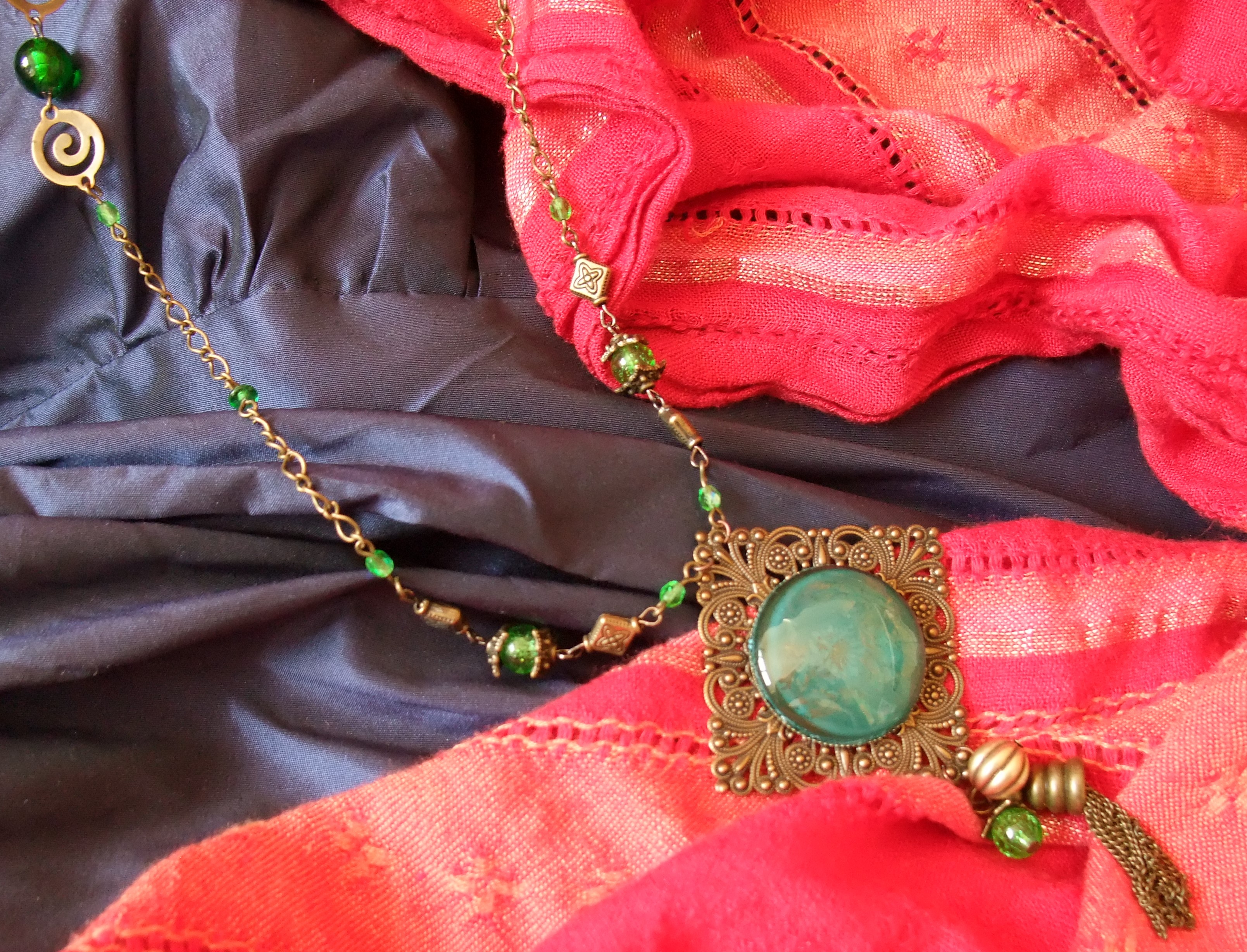robe bleue et écharpe rouge avec collier médaillon vert